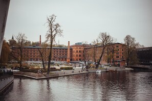 En utsikt över floden med en röd tegelbyggnad, en bro och en park där människor vistas.