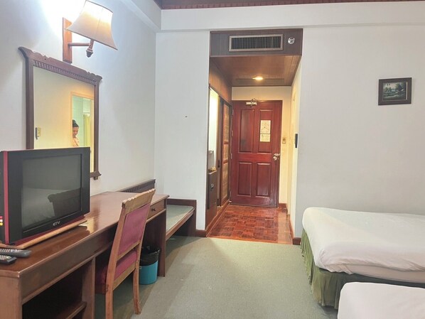 Habitación de hotel con televisión, escritorio, silla y cama.
