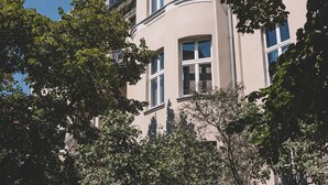 Un edificio de varios pisos con fachada curva, ventanas amplias y árboles circundantes.
