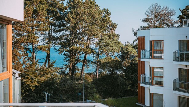 A modern building with multiple balconies, a clear view of the sea, and a lush green landscape. - 2Homerent Piedra | Relax with a Baltic Sea View (Gąski)