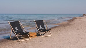 Two beach chairs with '2 HOME' branding on a sandy beach by the sea. - 2Homerent Piedra | Relax with a Baltic Sea View (Gąski)