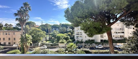 A balcony with a view of a residential area, including a parking lot and buildings.