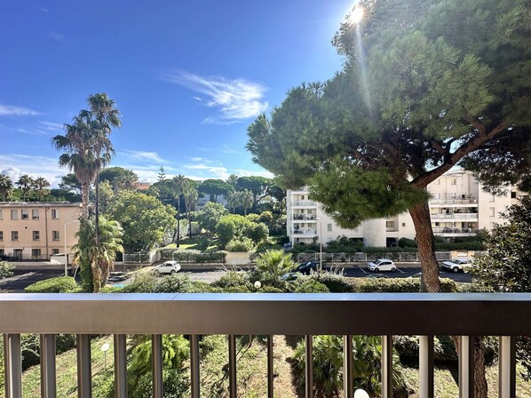 A balcony with a view of a residential area, including a parking lot and buildings.
