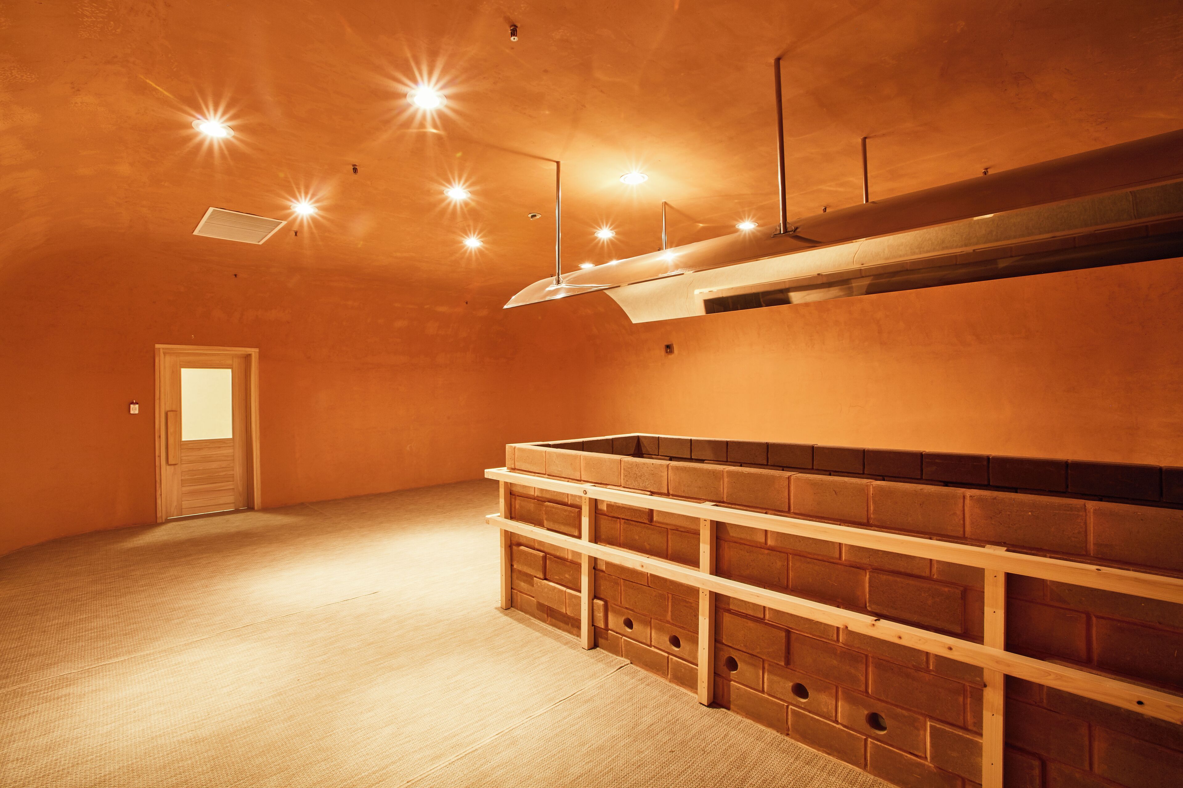 A room with a brick wall, a wooden bench, and a door.