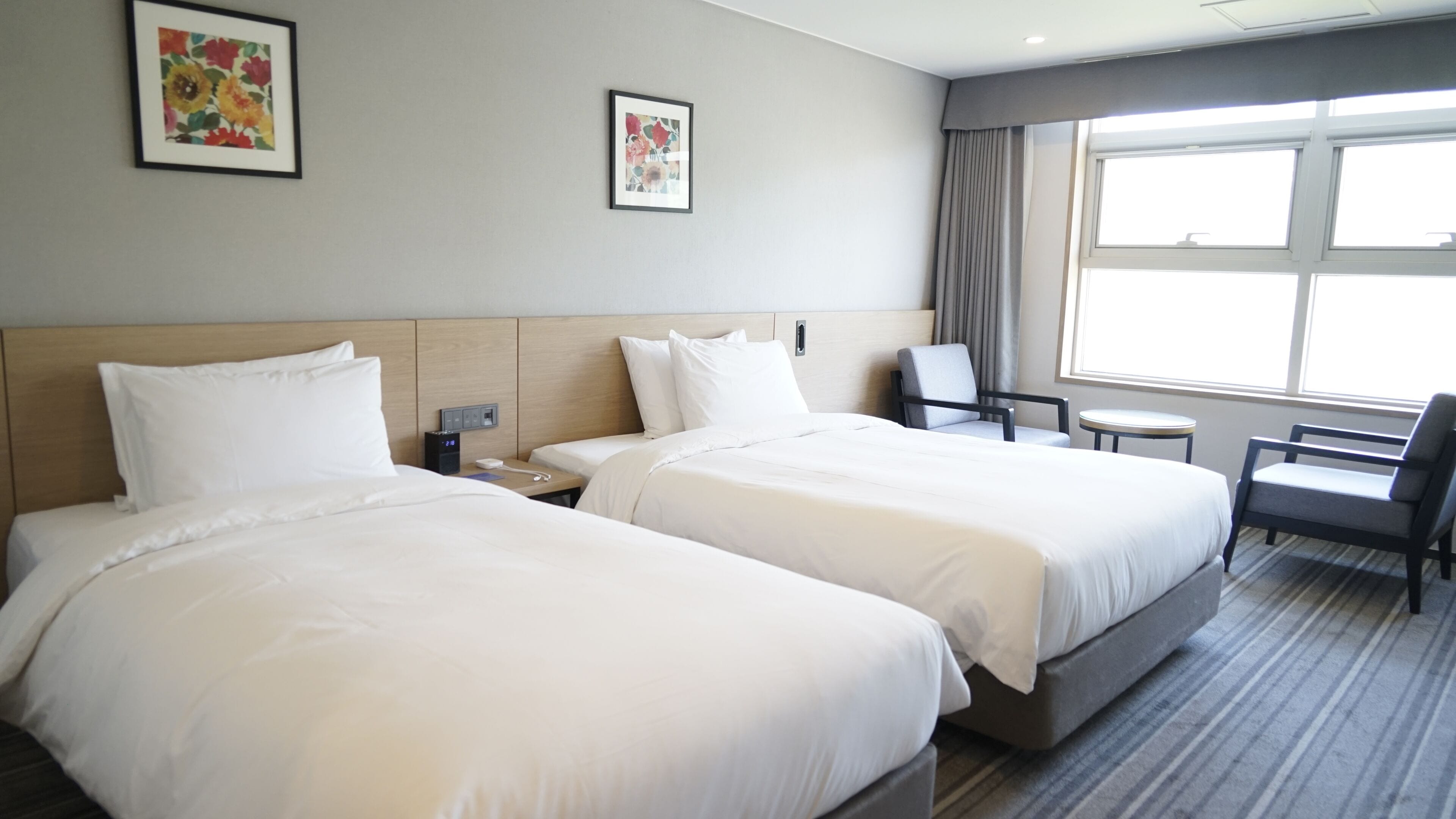 Ett hotellrum med två sängar, ett skrivbord, en stol och ett fönster.