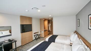Habitación de hotel con dos camas, un televisor, un escritorio con teléfono y un armario para abrigos.