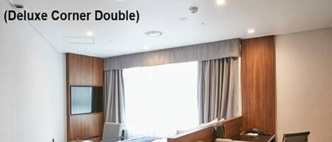 Una habitación de hotel con cama, escritorio, silla y un ventanal grande.