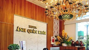 Un mostrador de recepción de hotel con detalles de madera, un candelabro y un letrero que dice 'HOTEL ÁNH QUÁN KHÔI'.