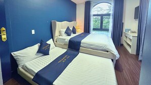 Habitación de hotel con dos camas, un escritorio y una ventana con cortinas.