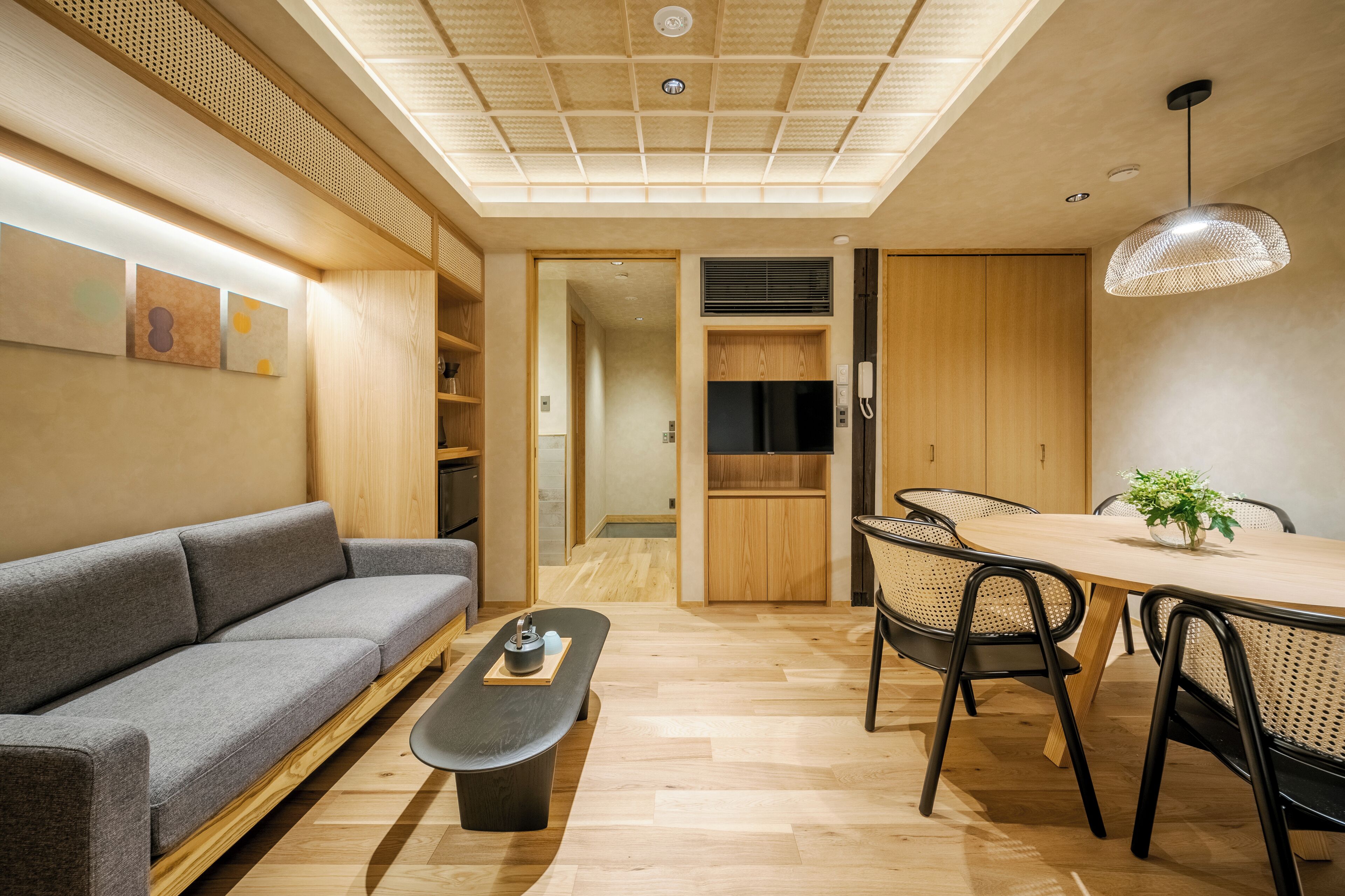Un salon moderne comprenant un canapé, une table basse, une table à manger, des chaises et un luminaire suspendu.
