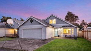 A residential house with a garage, a basketball hoop, and a well-maintained lawn. - Wonderful North End Seaside Home, Fenced Backyard, Backyard Patio, 1 Mile to Shops, Food, and Fun (Seaside)