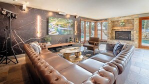 Ein modernes Wohnzimmer mit einer großen Ledersofa, einem Kamin aus Stein und einem großen Fenster mit Blick auf einen Pool.