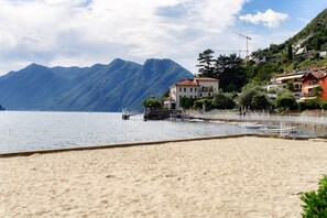 A beach with a mountain backdrop, a pier, and residential buildings.
