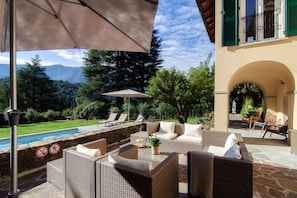 An outdoor patio with wicker furniture, a pool, and a view of mountains.