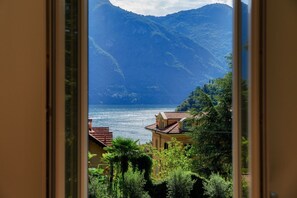 Vista costera con montañas, una masa de agua y edificios con tejados rojos.