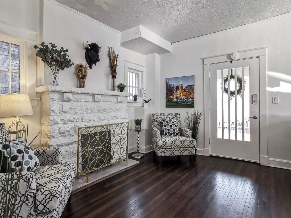 Una sala de estar con chimenea, un sillón estampado y una puerta decorada con un adorno navideño.