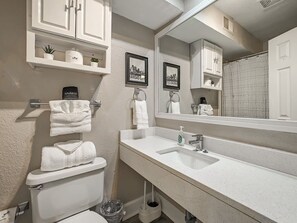 Un baño con un lavamanos blanco, un inodoro, un espejo y una cortina de ducha.