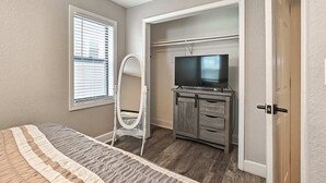 A bedroom with a bed, a TV on a stand, a wardrobe, and a window with blinds. - Cute Midtown 1 Bedroom (Kansas City)