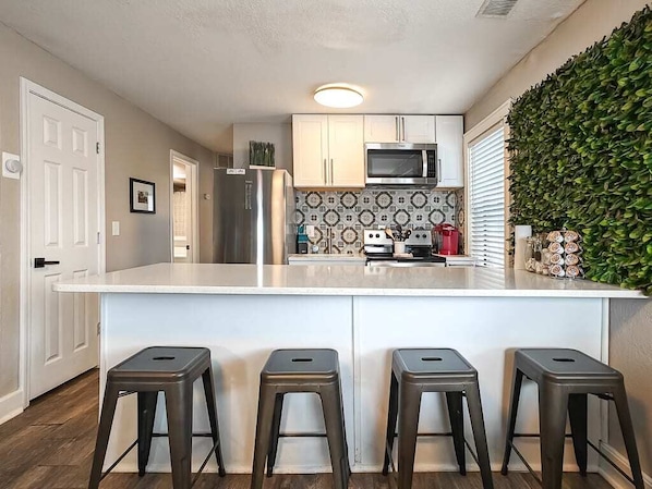 Una cocina moderna con una isla central, electrodomésticos de acero inoxidable y un salpicadero decorativo.