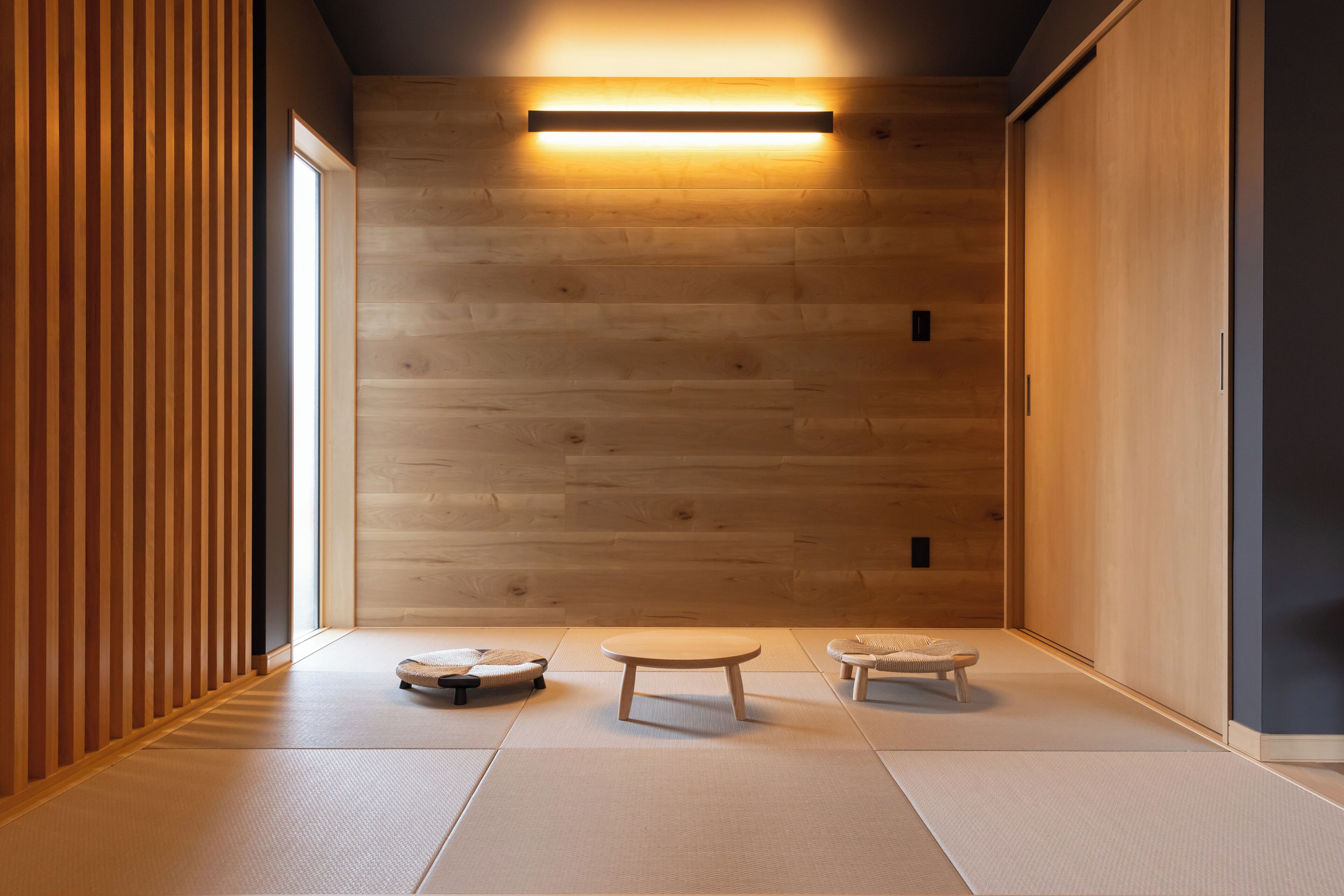 A minimalist room with tatami flooring, a low table, and two cushions.