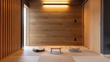 A minimalist room with tatami flooring, a low table, and two cushions.