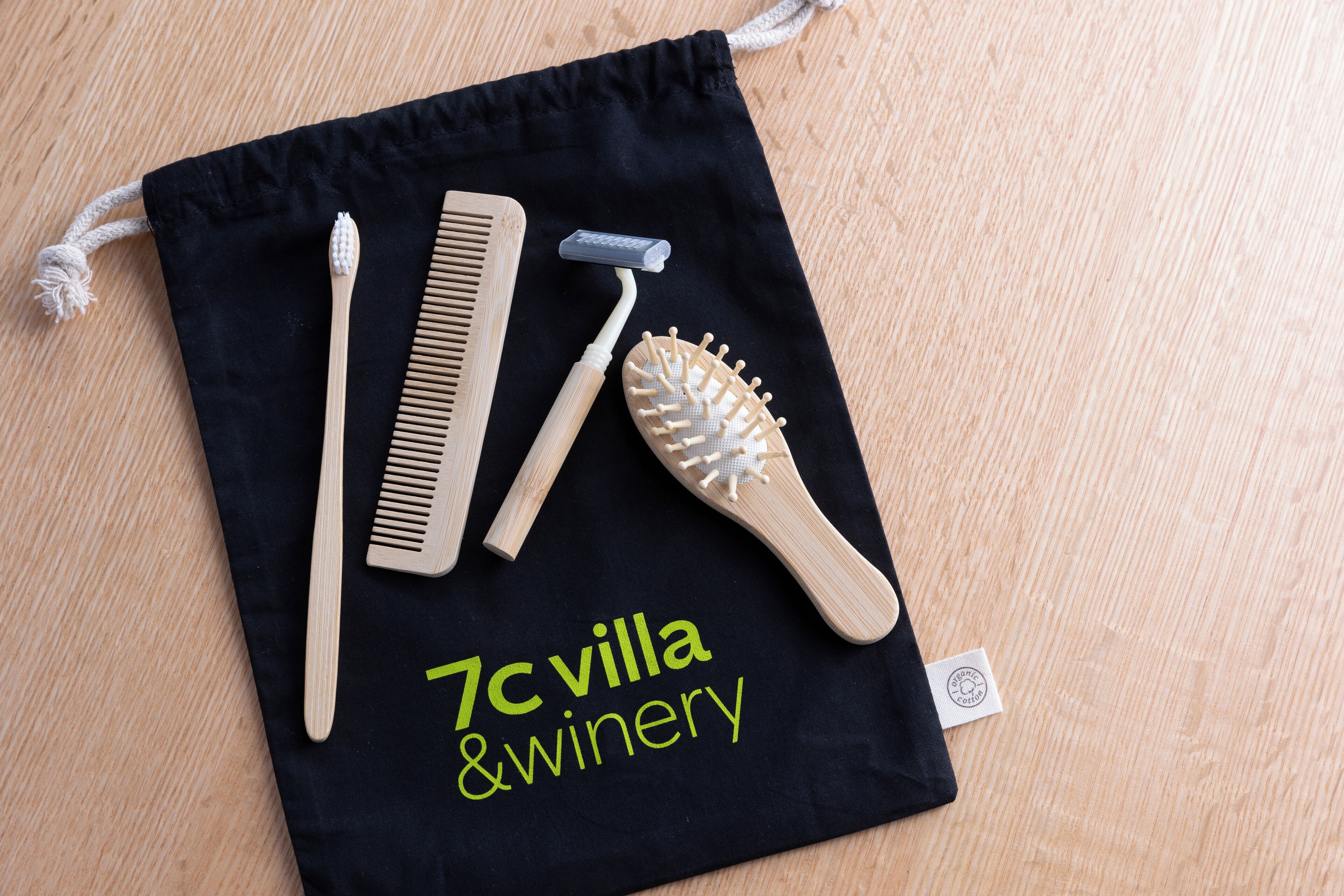 A black drawstring bag with a comb, toothbrush, and brush on a wooden surface.