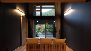 Une chambre moderne avec un banc en bois, une grande fenêtre donnant sur un paysage verdoyant et des lampes fixées au mur.