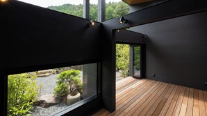 Un intérieur moderne avec de grandes fenêtres, une terrasse en bois et une vue sur un jardin.