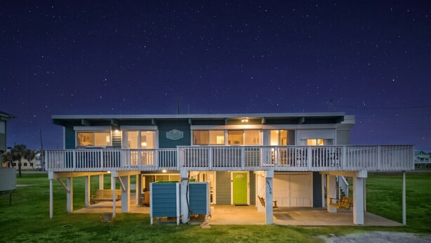 A two-story building with a balcony, a green door, and a swing set.