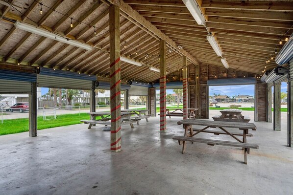 Un pabellón cubierto al aire libre con mesas de picnic y suelo de hormigón.