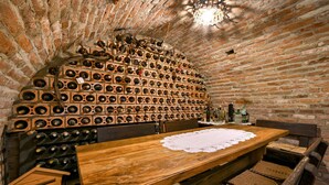 Un interior rústico de ladrillo con una mesa y sillas de madera, una estantería para vinos en la pared y una araña.