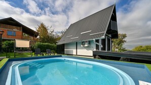 Una piscina con borde azul, rodeada de césped y una casa con techo inclinado.