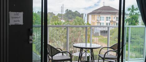 Un balcón con dos sillas y una mesa, con vistas a una zona residencial con casas y follaje.