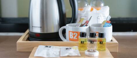 A tray with toiletries including B2 branded shampoo, conditioner, and a toothbrush, a kettle, and a mug with B2 branding.
