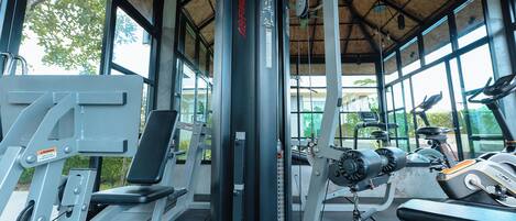 A gym with exercise equipment, large windows, and a thatched roof.