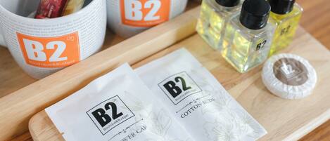 En træbakke med produkter fra B2 Boutique & Budget, herunder en badehætte og vatpinde.