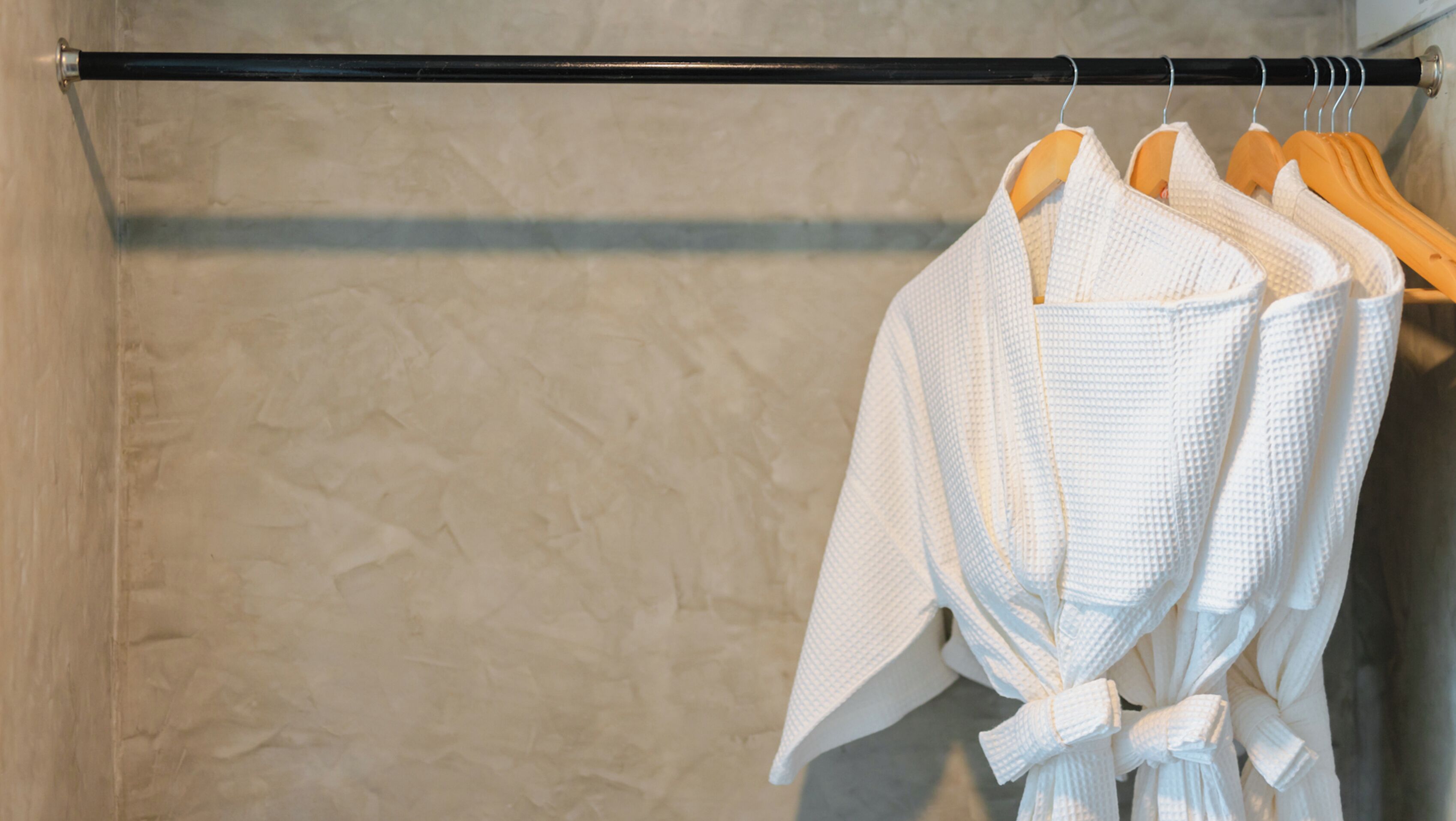 Une salle de bain avec un porte-serviettes sur lequel sont pliées des robes blanches.
