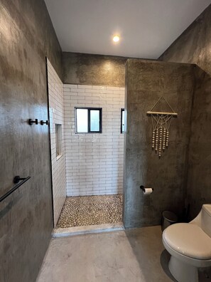 Bathroom features a shower area, toilet, and decorative wall hanging.