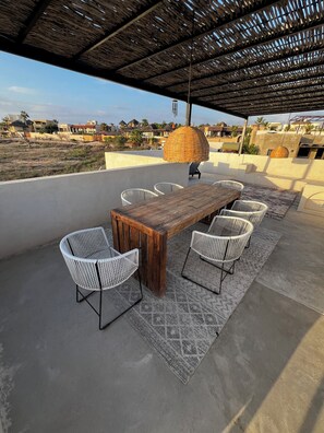 Enjoy al fresco dining under a charming roofed structure with a rustic table and comfortable seating for six.