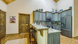 A kitchen with wooden cabinets, a granite countertop, and a stainless steel refrigerator. - 28 Acres: Home w/ Barn & Fire Pit Near Franklin! (Otto)