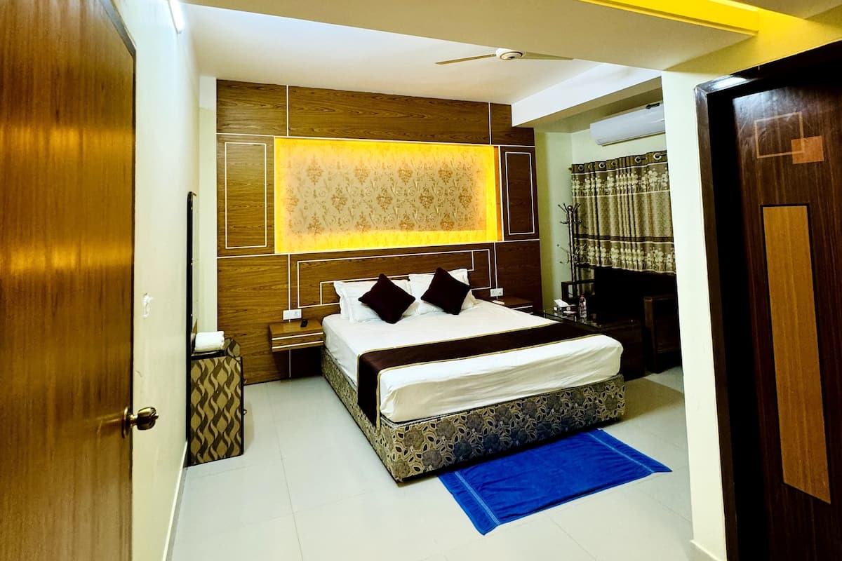 A modern bedroom with a large bed, a ceiling fan, and a blue area rug.