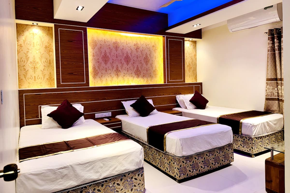 A hotel room with three beds, a ceiling fan, and a patterned wall.