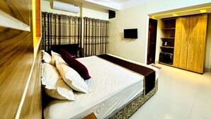 Un dormitorio con cama, cortinas, ventilador de techo, televisor y armario.