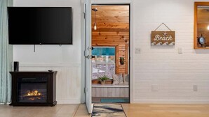 Una sala de estar con chimenea, televisor y una pared de madera con un letrero que dice 'Beach'.