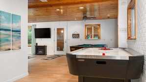 Una habitación amplia con mesa de billar, chimenea y televisor.