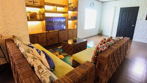 Una sala acogedora con un juego de sofá, un televisor de pantalla plana y un estante decorativo en la pared.