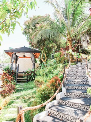 Un jardín con un mirador, una escalera y diversas plantas.