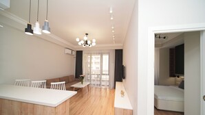 A modern living room with a sofa, a dining table, and a kitchen area with a counter.