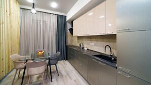 Een moderne keuken met een eethoek, met een glazen tafel, twee stoelen, een fruitmand en een spoelbak.
