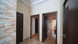 A hallway with a stone wall, wooden doors, and a tiled floor.